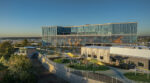 Metrocare Mental Health and Disability Innovation Center's modern building in Dallas, with large glass windows, a colorful mural, and a playground area surrounded by greenery.