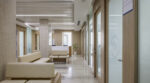 Rama Hospital OPD corridor with RH-branded frosted glass doors, cream benches, and marble flooring.